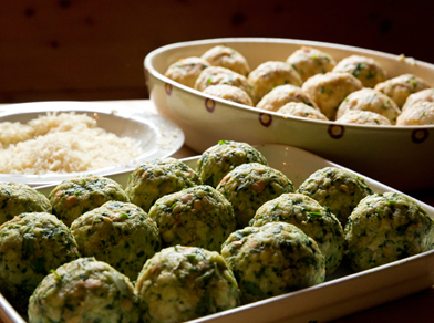Canederli freschi agli spinaci e formaggio su un vassoio, pronti per la cottura.