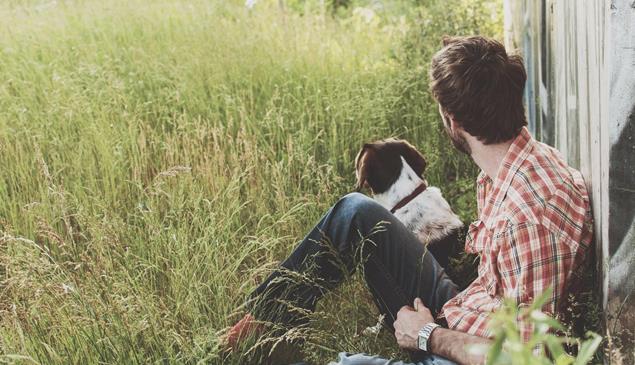 Un uomo e un cane seduti su un prato